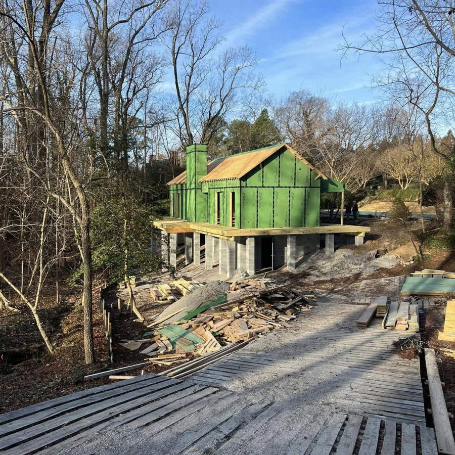 New House Construction In Wooded Area With Green Siding And Debris